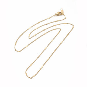 golden flat satellite curb chain necklace with lobster claw clasp on white background. 