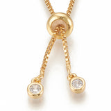 zoomed in golden slider bead and bezel set clear stone stopper beads on golden Bolo box chain necklace on white background. 