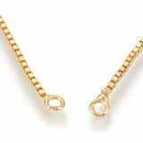 zoomed in golden jump rings on golden box chain on white background. 