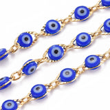 zoomed in section of golden textured link chains with blue "evil eye" beads on white background. 