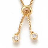 zoomed in golden slider bead and bezel set clear stone stopper beads on box chain Bolo necklace against white background. 