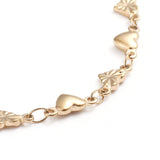 zoomed in section of golden heart link bracelet on white background. 