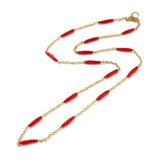 golden curb chain and red enamel bar link necklace with lobster claw clasp on white background. 