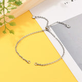 stainless steel bolo style cable chain bracelet making with slider bead and bezel set clear stone stopper beads on yellow, white and gray background with green leaves.. 