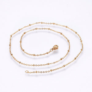 golden satellite cable chain necklace with lobster claw clasp on white background. 