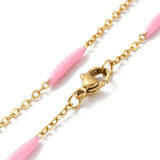 zoomed in sections of golden curb chain and pink enamel bar link necklace with lobster claw clasp on white background. 