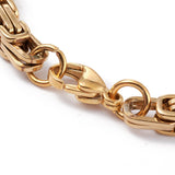 zoomed in lobster claw clasp section of Byzantine chain bracelet on white background. 