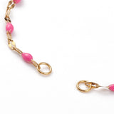 zoomed in section of golden link and pink enamel bracelet making where the jump rings are to attach item of your choice on a white background. 