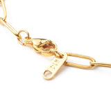 zoomed in section of golden medium link paperclip chain necklace with lobster claw clasp on white background. 